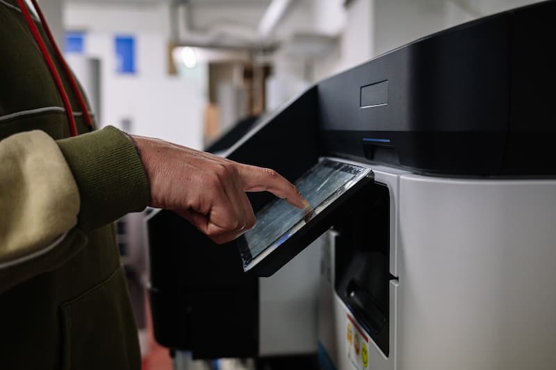 Hand using the touchscreen of a full-size multifunction copier