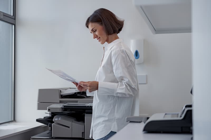 Office manager reviewing printed pages at the office printers