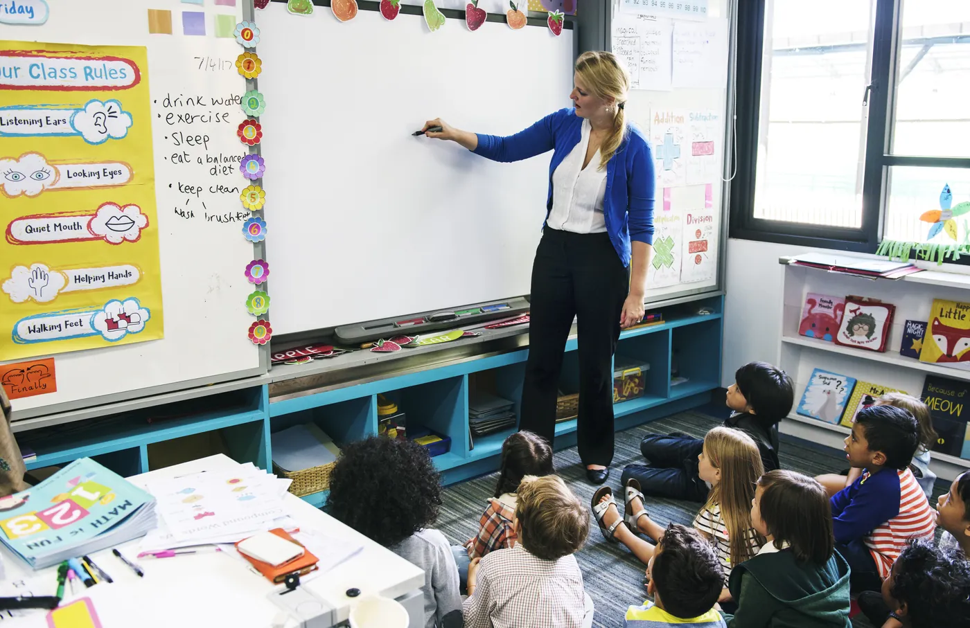 Teacher writing on an interactive whiteboard in front of students