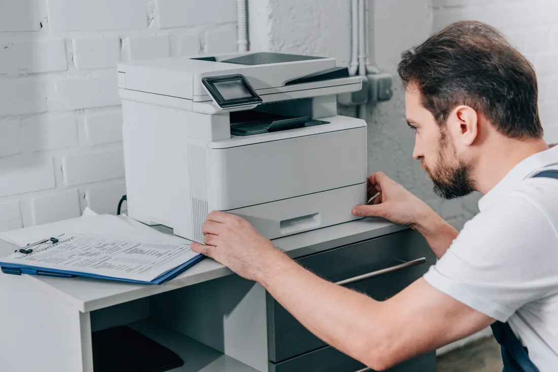 Technician servicing a multifunction printer in a bright office